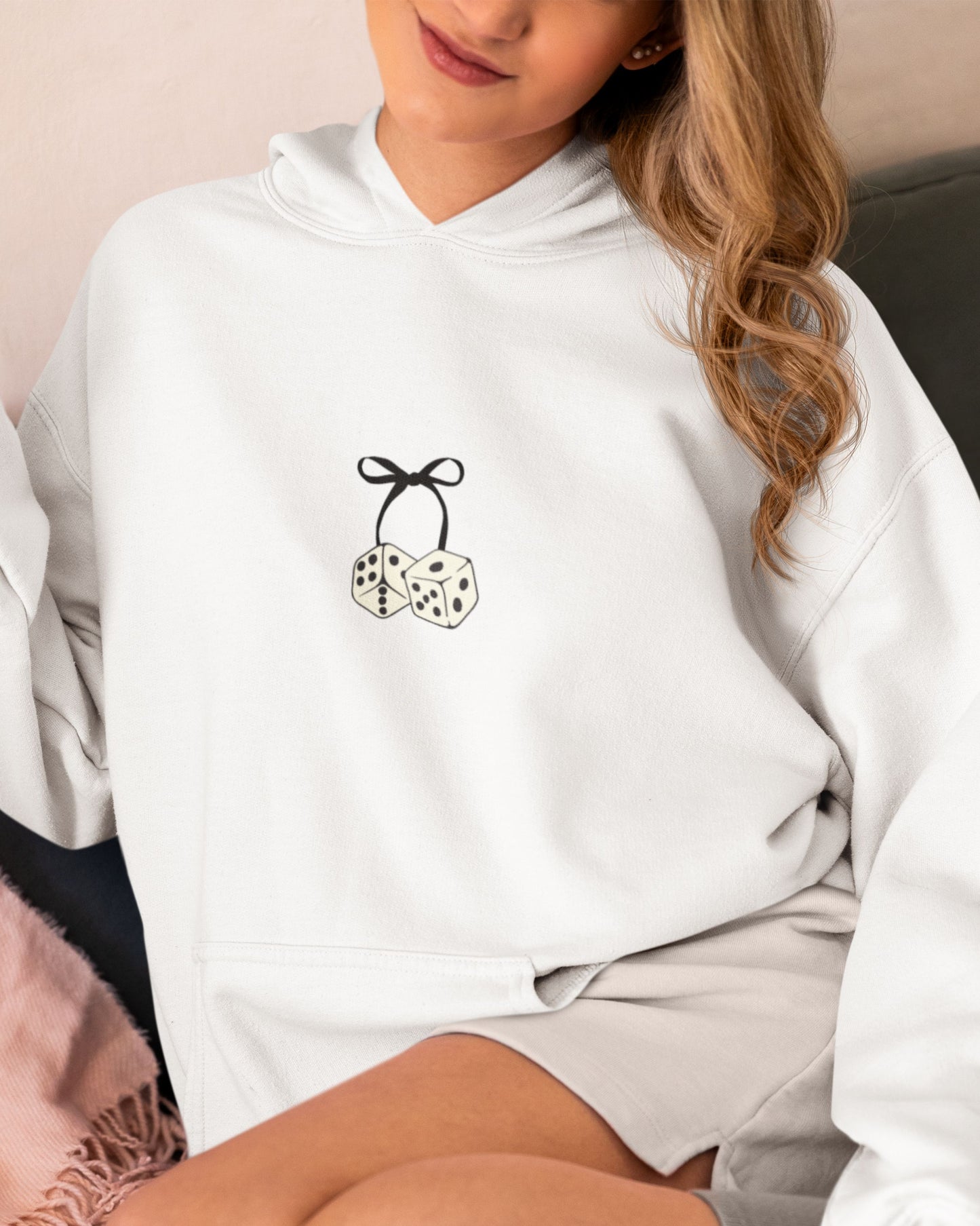 Blonde girl sitting on couch in cute Dice & Bow Lucky Days hoodie.