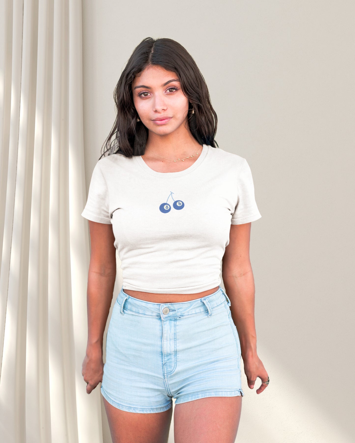 Model wearing a white crop top with a eight ball cherry design