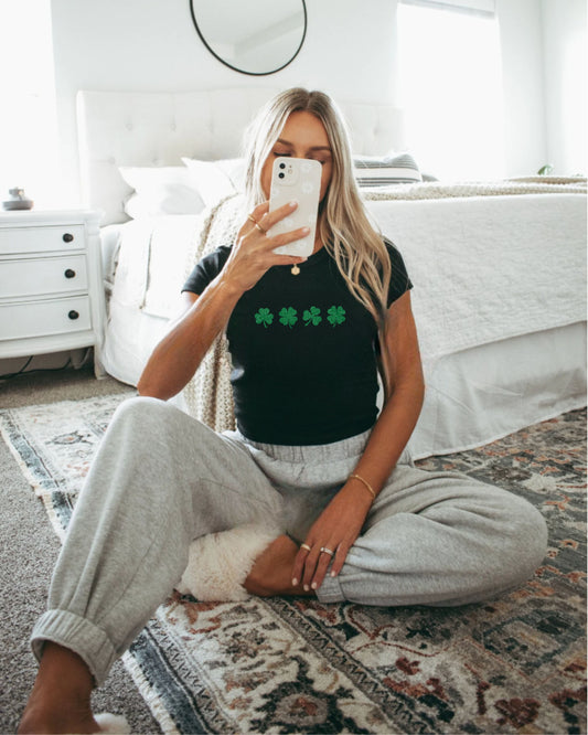 Mirror selfie of blonde girl wearing the Lucky Days black shamrock baby tee