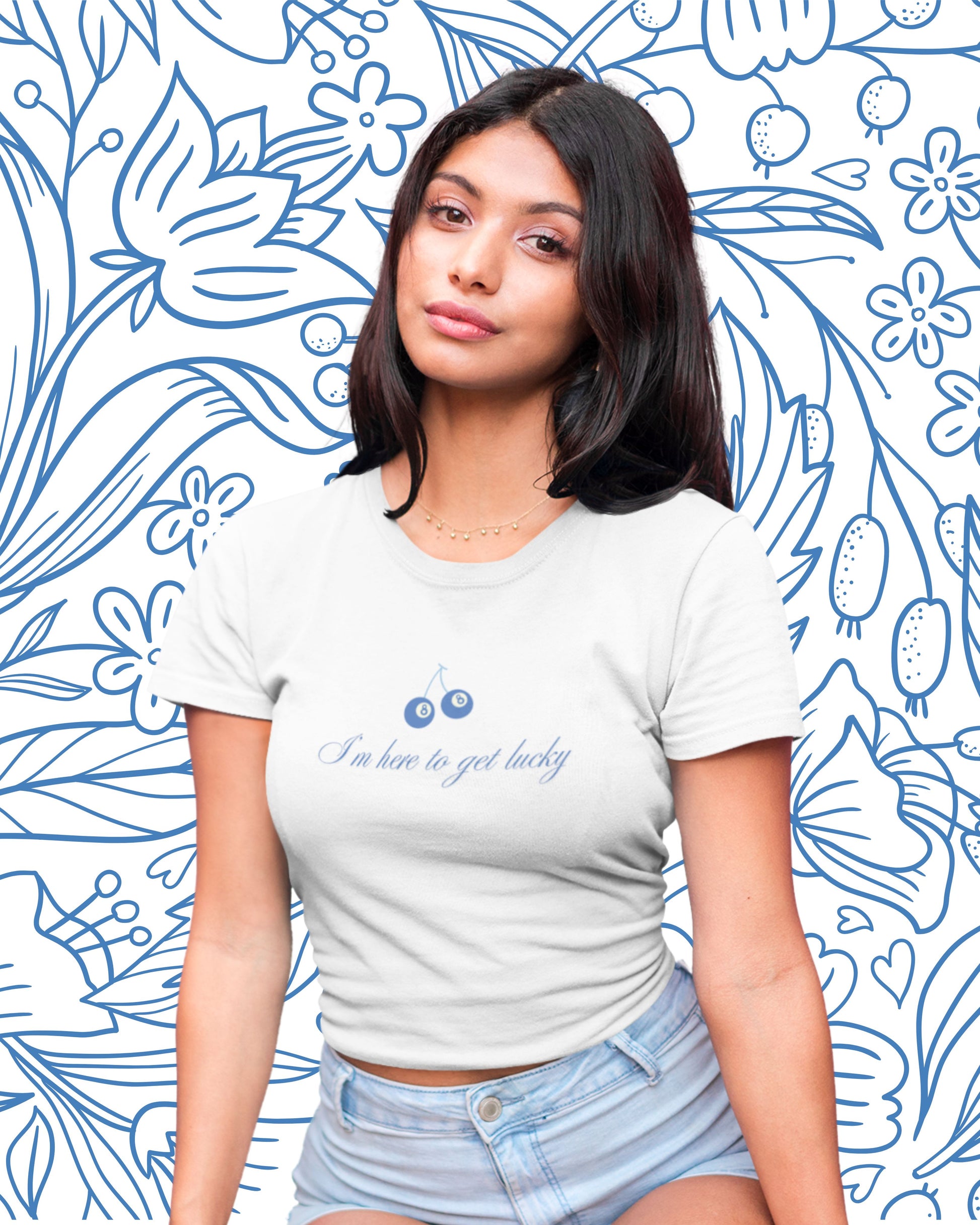 Cute girl wearing white baby tee that say im here to get lucky. The design features a cherry style graphic with eight balls as the cherries.